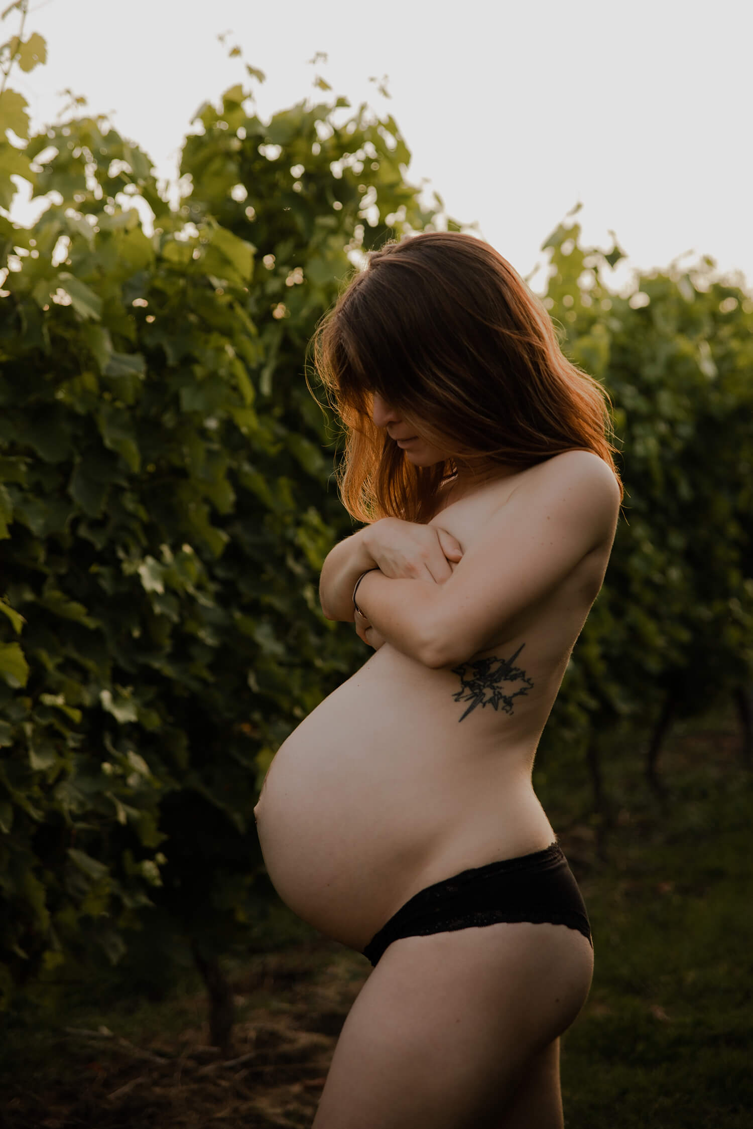 Une femme enceinte pose en sous-vêtements dans les vignes. De profil, on voit bien son joli ventre rond. Une photo prise par Meyline Esparcieux, photographe grossesse Dax, Landes.