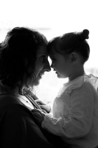 Une maman et son enfant sont front contre front en contre-jour pendant leur séance photo famille. Une photo silhouette créée par Meyline Esparcieux, photographe Dax.
