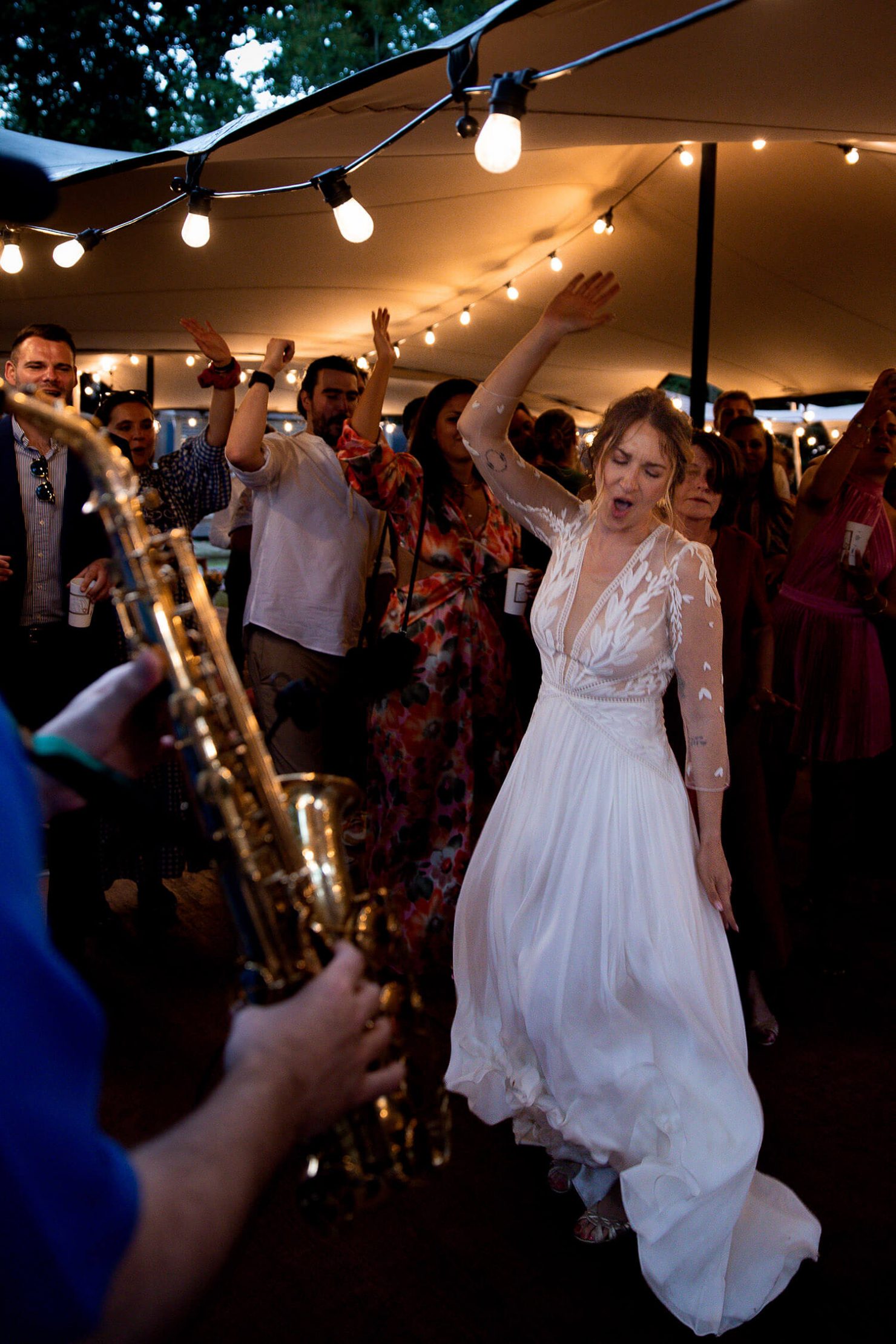 Pendant le cocktail, la mariée danse, chante et saute en l'air pendant que le saxophoniste joue et met l'ambiance. Un moment fun capté par Meyline Esparcieux, photographe de mariage dans les Landes, basée à Dax.