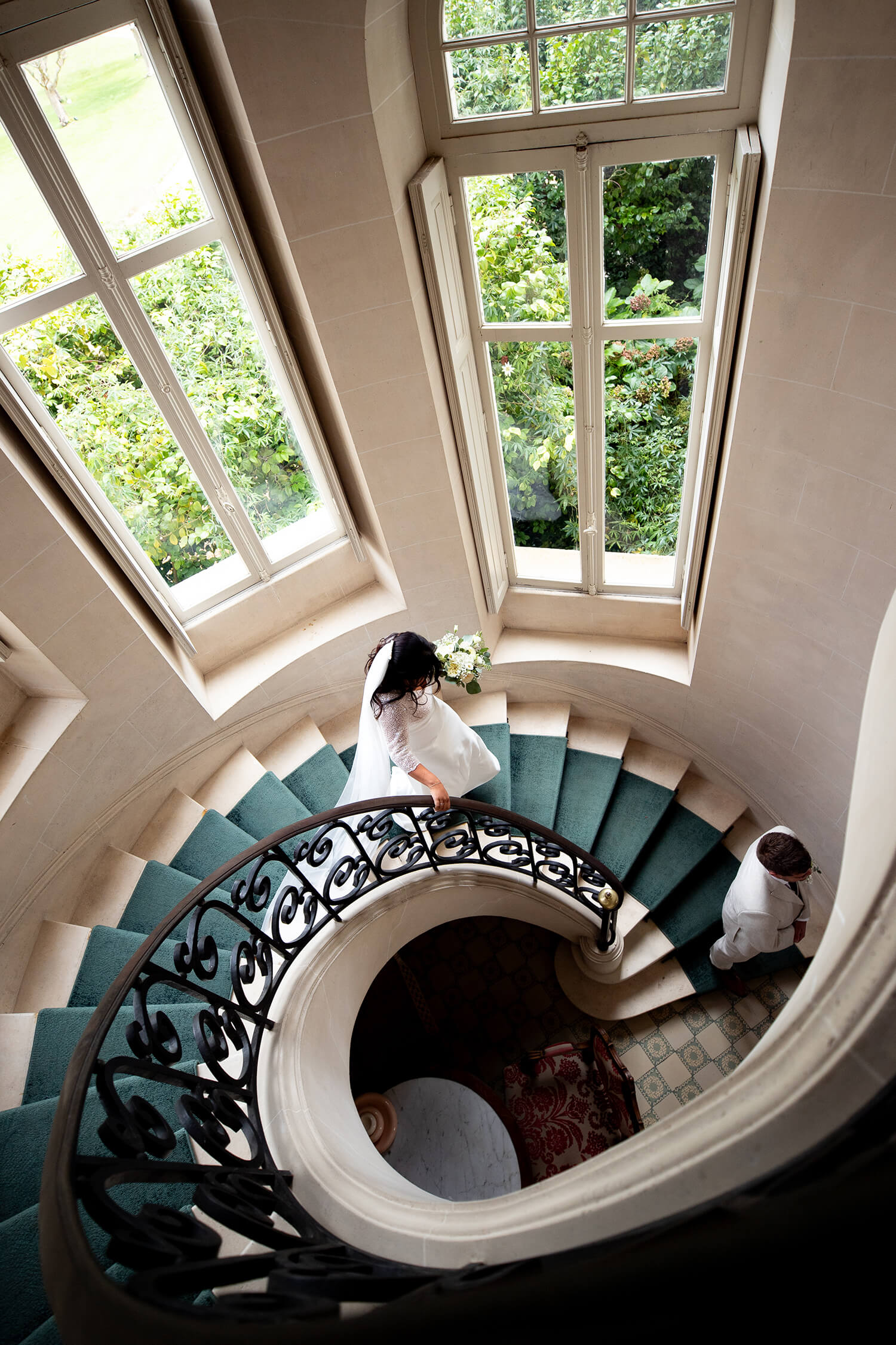 Les mariés descendent les escaliers en colimaçon du domaine de mariage Château Clair de Lune à Biarritz. Le portrait de mariage est pris du dessus et est composé comme un tableau. Cette image est signée par Meyline Esparcieux, photographe de mariage dans les Landes, basée à Dax.
