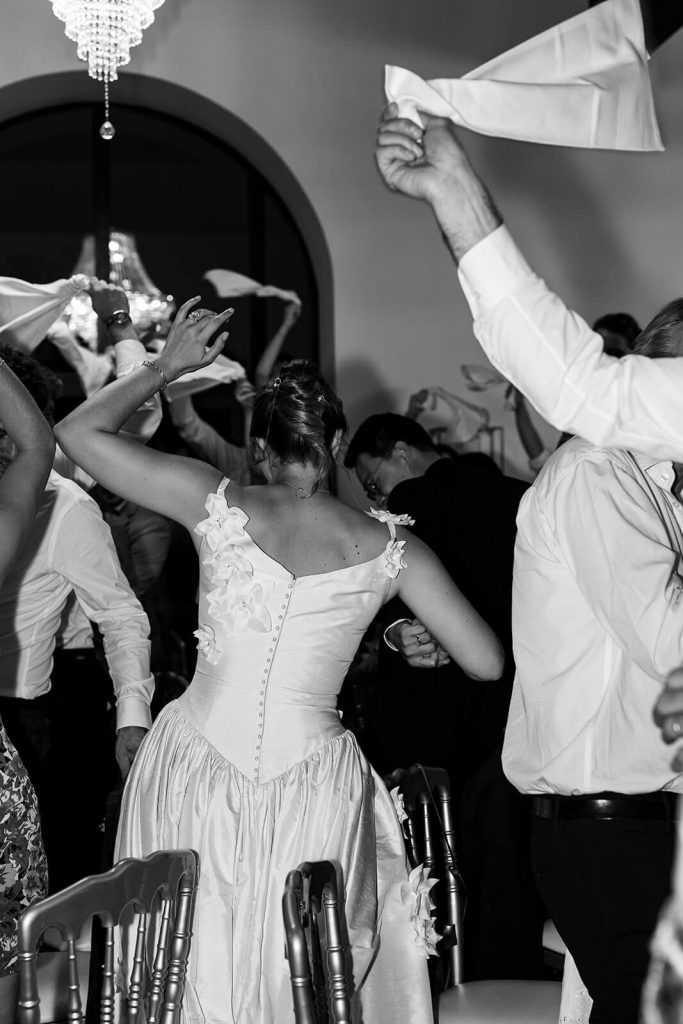 La mariée rentre dans la salle de réception de mariage en dansant, les invités sont en folie autour d'elle. Un moment de fête capté par Meyline Esparcieux, photographe mariage Dax Landes.