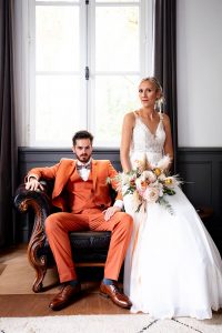 Un couple de mariés assis sur un fauteuil en cuir. Un portrait de mariage d'inspiration vintage réalisé par Meyline Esparcieux, photographe Dax.