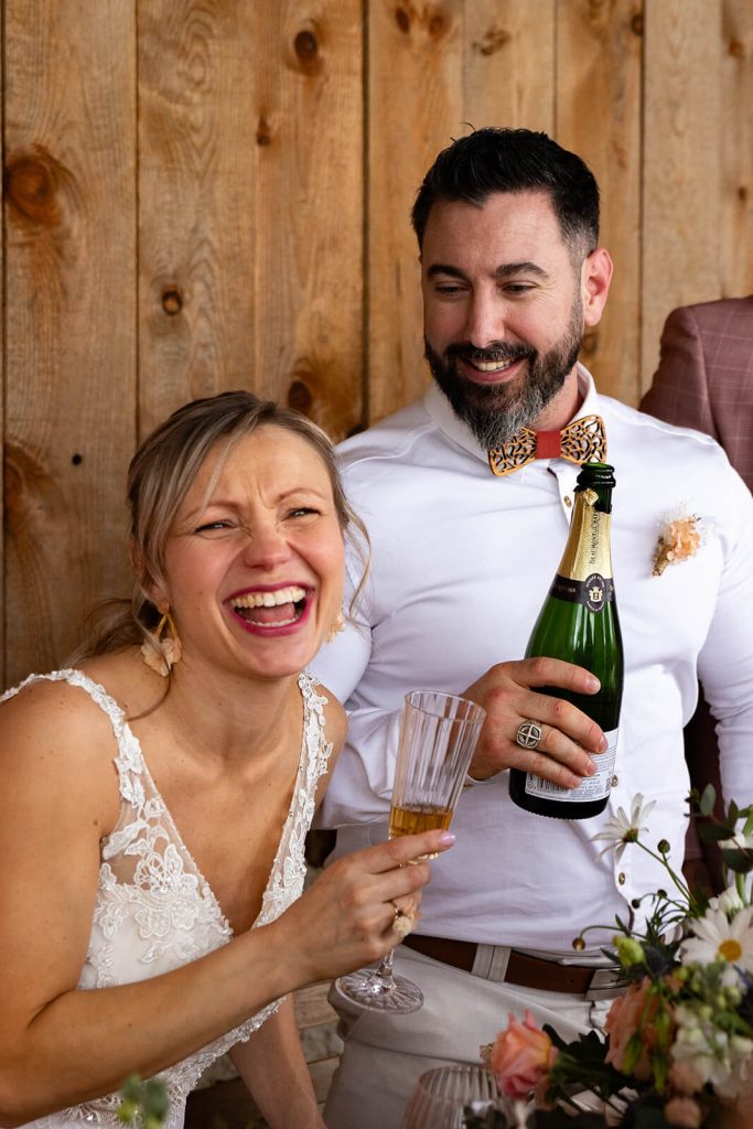 La mariée explose de rire pendant que le marié lui remplit sa coupe de champagne. Un moment fun capté par Meyline Esparcieux dans les Landes.