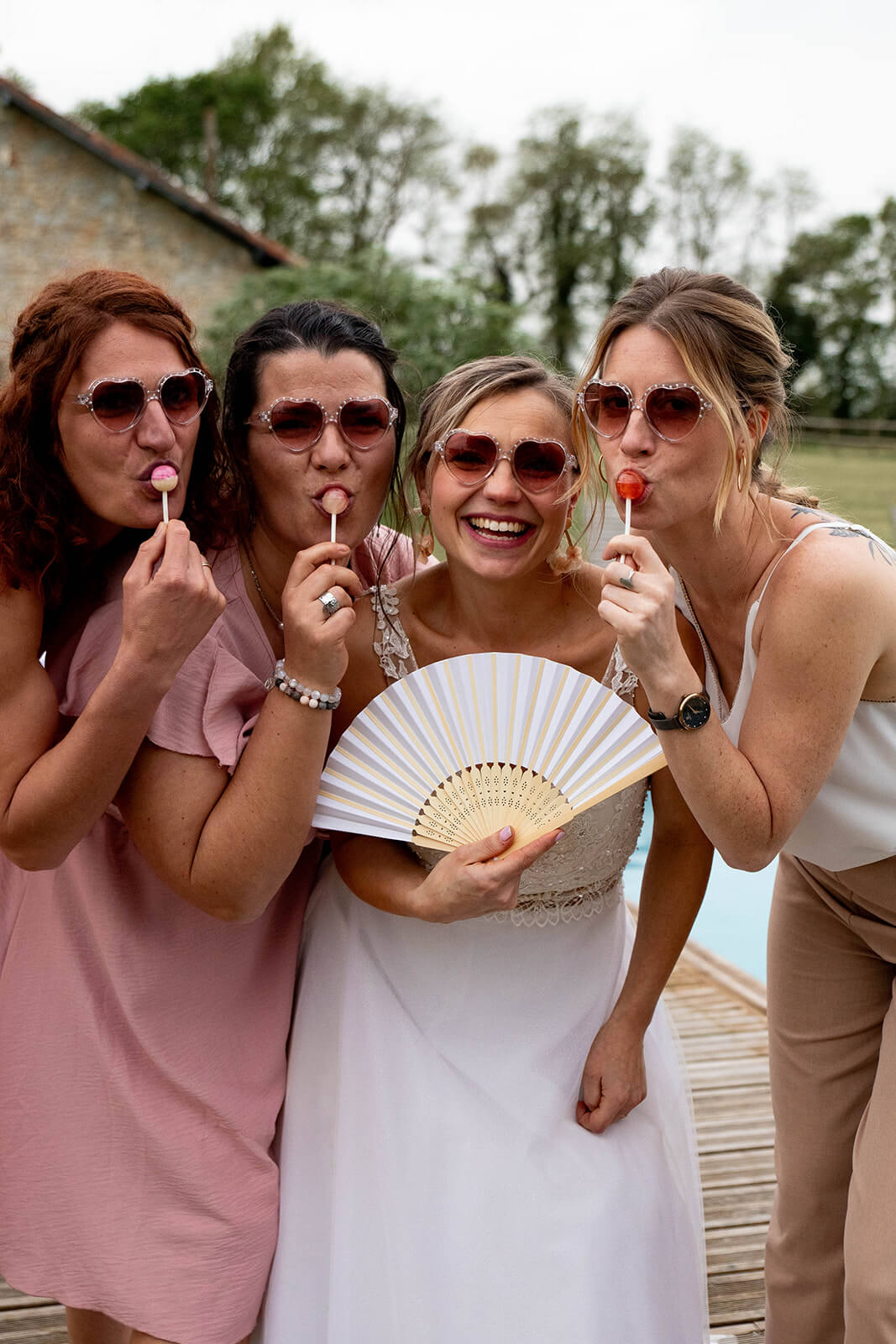 La mariée et ses témoins ont des lunettes de soleil, un éventail et des sucettes. Un moment fun capturé par Meyline Esparcieux, photographe mariage Dax Landes.