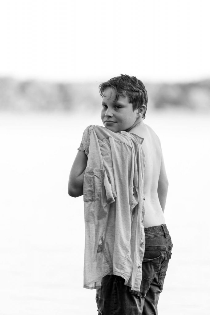 Un enfant est devant un lac dans les Landes. Portrait d'enfant créé par Meyline Esparcieux, photographe mariage Dax Landes.